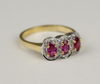 A 14ct yellow gold ruby and diamond triple cluster ring, Size N