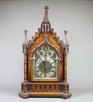 A Victorian Thwaites style triple fusee quarter repeating grand sonnier Cathedral bracket clock, having an 11 1/2" arched silvered dial with Roman numerals, slow/fast indicator and chime/silent indicator, striking on 8 bells and gong, contained in a heavily carved Gothic oak case 
