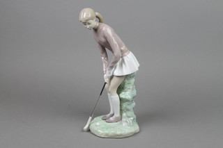A Lladro figure of a female golfer on raised base 12" 