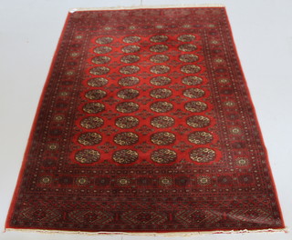 A Wilton red ground Bokhara style rug with octagons to the centre 77" x 56"