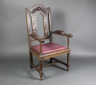 A Victorian carved oak open arm chair, heavily carved throughout with drop in seat, with turned and block supports raised on an H framed stretcher 