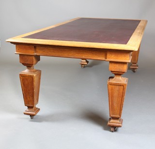 A Victorian light oak rectangular library table with inset brown writing surface, raised on 4 massive square tapered supports 29"h x 84"w x 41 1/2"d 