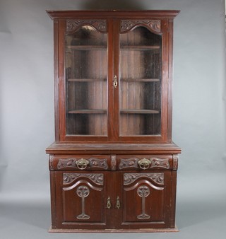 An Edwardian Art Nouveau carved mahogany bookcase on cabinet, the upper section with moulded cornice, the interior fitted adjustable shelves enclosed by arched panelled doors, the base fitted 2 long drawers above a double cupboard 80 1/2"h x 48"w x 18"d 