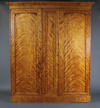 A Victorian satin birch double wardrobe with moulded cornice enclosed by panelled doors with pierced fret work decoration, raised on a platform base 75" x 64"w x 24"d