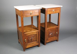 A pair of French Art Nouveau square oak bedside tables with white veined marble tops, fitted a drawer above a recess and cupboard enclosed by a panelled door 33 1/2"h x 16 1/2"w 