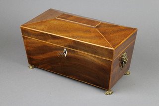A Georgian bleached mahogany tea caddy of sarcophagus form with brass lion mask handles and ivory escutcheon, inlaid satinwood stringing and raised on gilt metal paw feet 5 1/2"h x 12"w x 6"d 