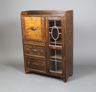 An Art Nouveau oak student's bureau the raised back the three-quarter gallery, fitted a fall front above 2 long drawers and having a panelled cupboard to the side enclosed by lead glazed panelled doors 39"h x 28 1/2"w x 11"d 