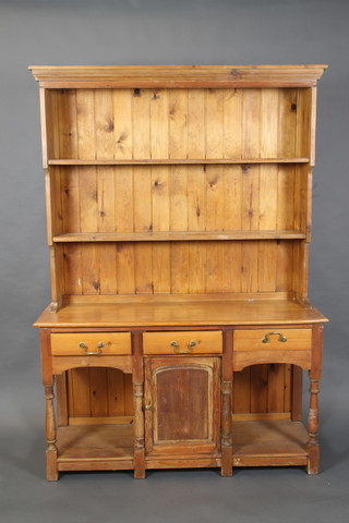 A pine dresser, the raised back with moulded cornice above 2 shelves, the base fitted 3 short drawers above cupboard, flanked by recesses, raised on turned and block supports 74"h x 52"w x 17"d 