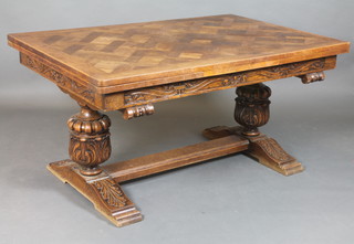 An oak refectory draw leaf dining table with parquetry top raised on massive cup and cover supports with H framed stretcher 28 1/2"h x 59" when closed, x 99" when open