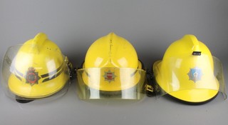 A yellow Ministry of Defence Fireman's helmet with visor, ditto East Sussex Fire Brigade and 1 other 