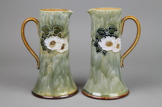 A pair of Royal Doulton tapered jugs, the green ground decorated with stylised flowers 8 1/2" , 1 cracked