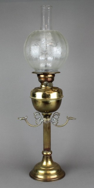 A brass oil lamp with etched glass shade raised on a fluted column 