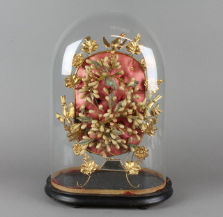 A 19th Century French bridal head dress mounted on a pressed gilt metal frame decorated birds with reeds and leaf decoration, contained under a glass dome 