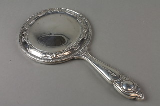 An Edwardian repousse silver circular hand mirror with swags and scrolls, Birmingham 1907
