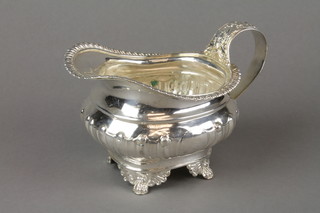 A Georgian demi-fluted cream jug with reeded rim and floral decorated S scroll handle on claw feet, London 1819, approx. 238 grams