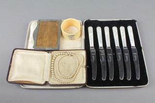 A silver photograph frame Birmingham 1924 4" x 2 3/4", a napkin ring, a cased set of knives and a string of imitation pearls
