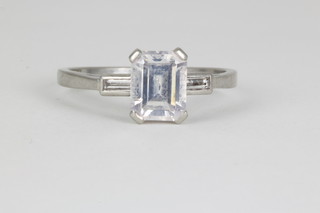 A platinum emerald cut diamond dress ring, the centre stone approx. 1.35ct flanked by a baguette cut diamond to each shoulder, size O.  