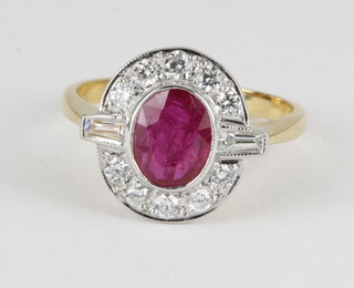 An 18ct yellow gold ruby and diamond cluster ring, the centre oval cut ruby approx. 1.4ct surrounded by 10 brilliant cut diamonds and baguette cut diamonds, size L 1/2