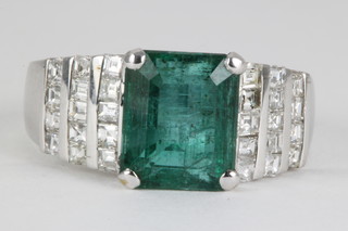 A 14ct white gold emerald and diamond stepped mount ring, the emerald cut centre stone approx 4.2ct flanked by 26 princess cut diamonds approx. 1ct 