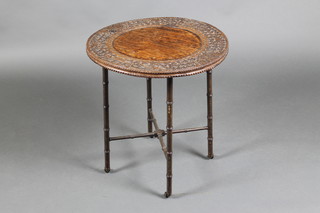 A circular Indian carved rosewood table, raised on an associated bamboo stand with X framed stretcher 21"h x 20"diam