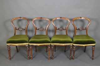 A set of 4 Victorian walnut balloon back dining chairs with carved mid rails, the seats of serpentine outline, raised on turned supports