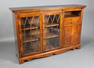 A Georgian style mahogany bookcase with moulded and dentil cornice, fitted shelves enclosed by an astragal glazed panelled door, flanked by a niche above drawer and cupboard, having fluted columns to the sides 83"h x 58"w x 14"d