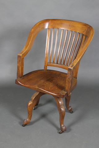 An Edwardian oak tub back office swivel chair raised on cabriole supports  