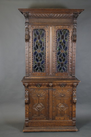 A carved oak Flemish bookcase on cabinet, the upper section with carved cornice and shelved interior enclosed by lead glazed panelled doors, the base fitted 2 short drawers above a pair of cupboards enclosed by panelled doors 95"h x 45"w x 20"d 