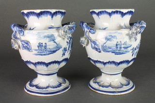 A pair of early 19th Century Continental blue and white urn shaped vases with splayed foot, decorated with panels of figures in rural settings and sprays of flowers, with applied rustic handles and flower head terminals 6" 