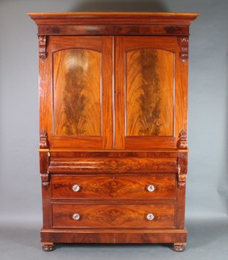 A Victorian mahogany linen press, the upper section with moulded cornice, fitted 2 shelves enclosed by arched panelled doors and with vitruvian scrolls to the side, the base fitted 1 long secret drawer above 2 long drawers with glass handles, raised on bun feet 87"h x 60"w x 25"d 