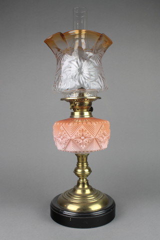 A Victorian octagonal peach glass oil lamp reservoir raised on a brass base, with an associated shade 