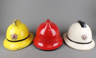 A yellow East Sussex Fire Brigade helmet, a white South Yorkshire County Fire Service helmet and a red fireman's helmet