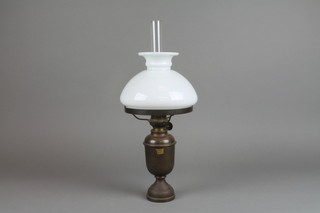A gilt metal oil lamp with opaque glass shade and clear glass chimney