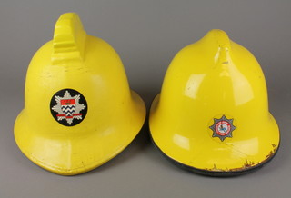A yellow London Fire Brigade fireman's helmet and a yellow County of Avon Fire Brigade helmet 