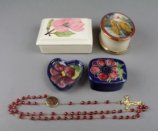 A Moorcroft rectangular box and cover, the cream ground with a pink flower 4 1/2", a ditto rounded rectangular blue box and cover with floral lid 3" and a ditto heart shaped blue dish decorated with a flower head 2 1/2", an oval trinket box PLEASE NOTE: The oval trinket box and rosary have been withdrawn from this lot
