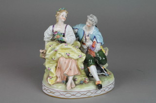 An early 20th Century Continental figure group of a couple seated on a wall, with applied floral decoration on a raised gilt base 6" 