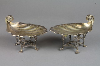 A pair of silver gilt shell shaped bon bon dishes on raised legs with Roman warrior masks and claw feet, London 1927, 340 grams