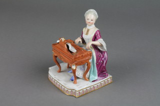A 19th Century Meissen figure of a lady sitting at a piano on a Rococo stool with a raised base 5"
