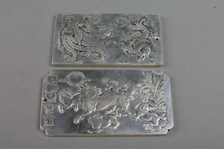 A Chinese white metal plaque with symbols of the zodiac, a ditto with a family of shi shi and characters
