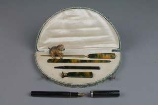 A 1930's cased desk set comprising a marble effect Bakelite paperknife, pen holder, pencil and desk seal, a Sheaffer fountain pen and a soft metal figure of a dog 