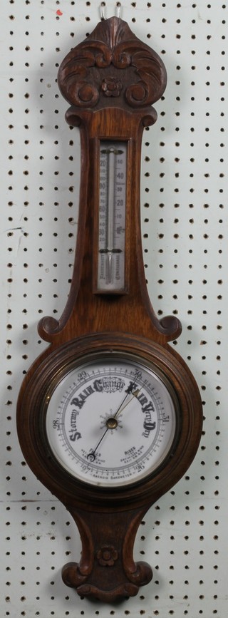 An Edwardian aneroid barometer and thermometer contained in a carved oak wheel case 