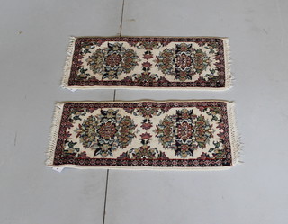 A pair of white ground Persian slip rugs with floral decoration 25" x 12"