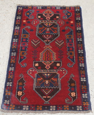 A red ground Persian Balochi rug with 2 stylised diamonds to the centre 58" x 33" 