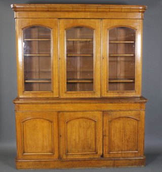 A Victorian light oak D shaped bookcase on cabinet with moulded cornice, the upper section enclosed by panelled doors, the base fitted 3 cupboards enclosed by panelled doors 88"h x 71"w x 20"d 