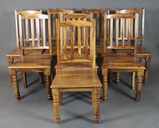 A set of 8 Indian hardwood stick and rail back dining chairs with solid seats raised on turned supports 