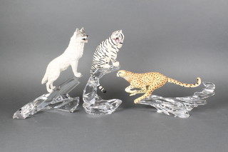 A Franklin Mint figure of a leopard on a glass base 14", a ditto snow tiger 14" and a wolf 14" 