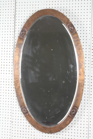 An Art Nouveau oval bevelled plate wall mirror contained in a planished copper frame 18 1/2" x 31 1/2" 