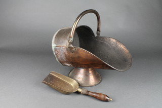 A copper helmet shaped coal scuttle with brass shovel and turned wooden handle