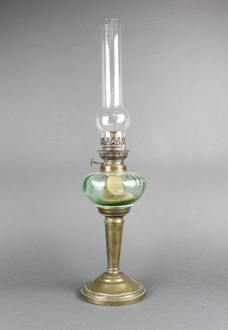 A Victorian green glass and brass oil lamp, raised on a tapering brass column 23", complete with clear glass chimney 