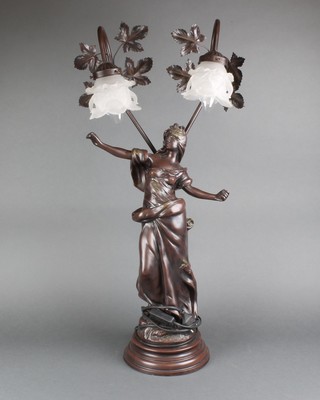 An Art Nouveau style bronzed twin light table lamp in the form of a standing lady with arms outstretched 